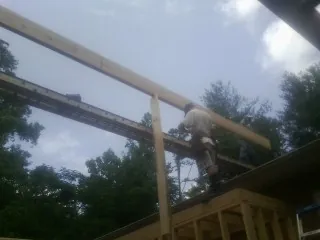 Carpenter setting a ridge beam over a new addition frame — Ice Dam Removal by Roofing Brothers in North Truro
