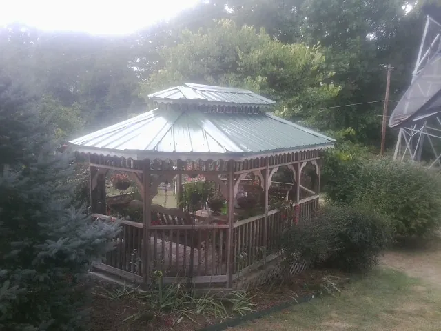 Green metal roof on a backyard gazebo surrounded by garden beds in North Truro