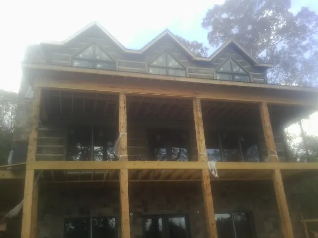 Dormers and porch framing on a large log home under construction — Roof Coating work by our crew in North Truro