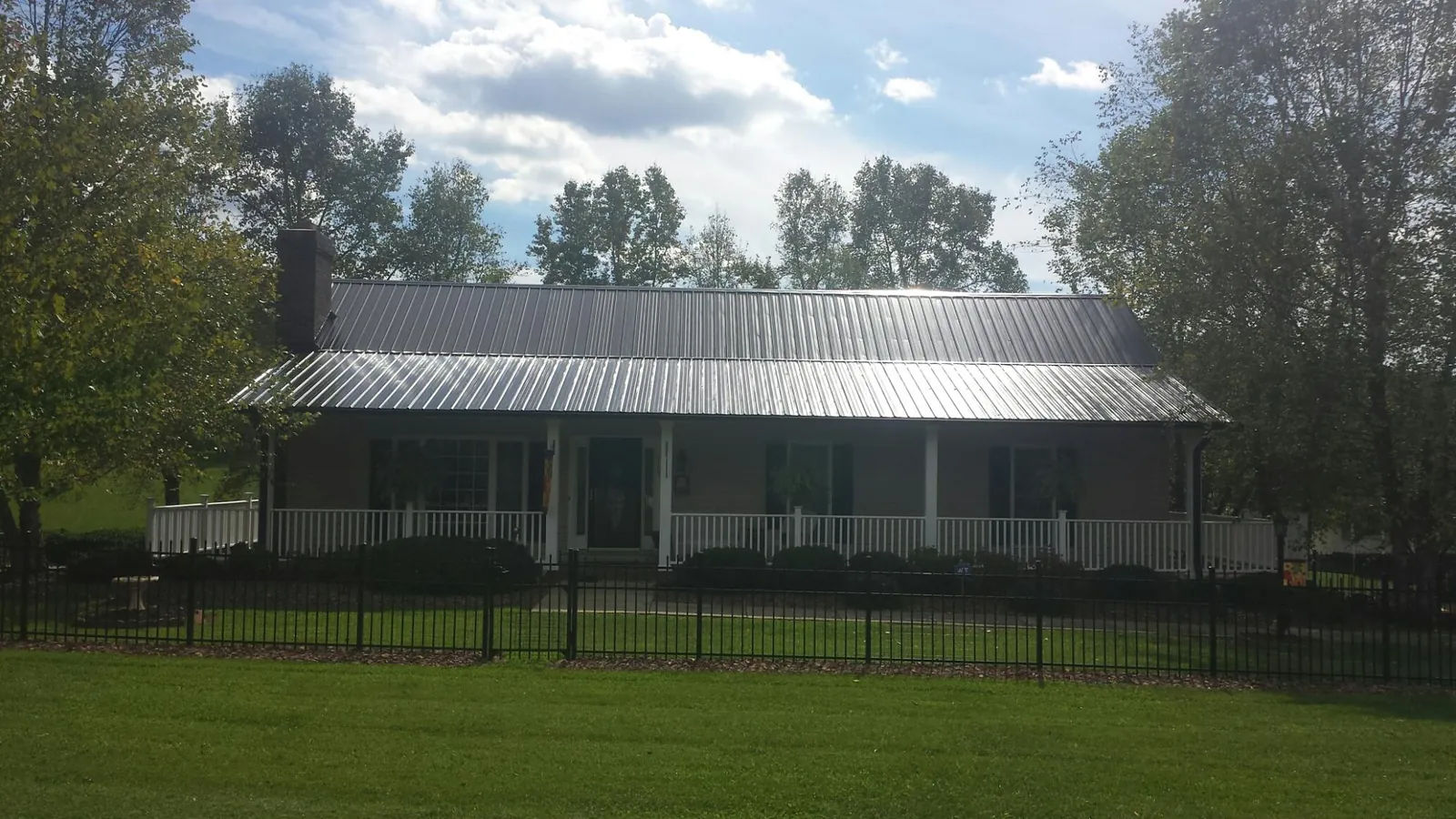 Gray metal roof on a brick ranch with a full width front porch — Gutter Guard Installation work by our crew in North Truro