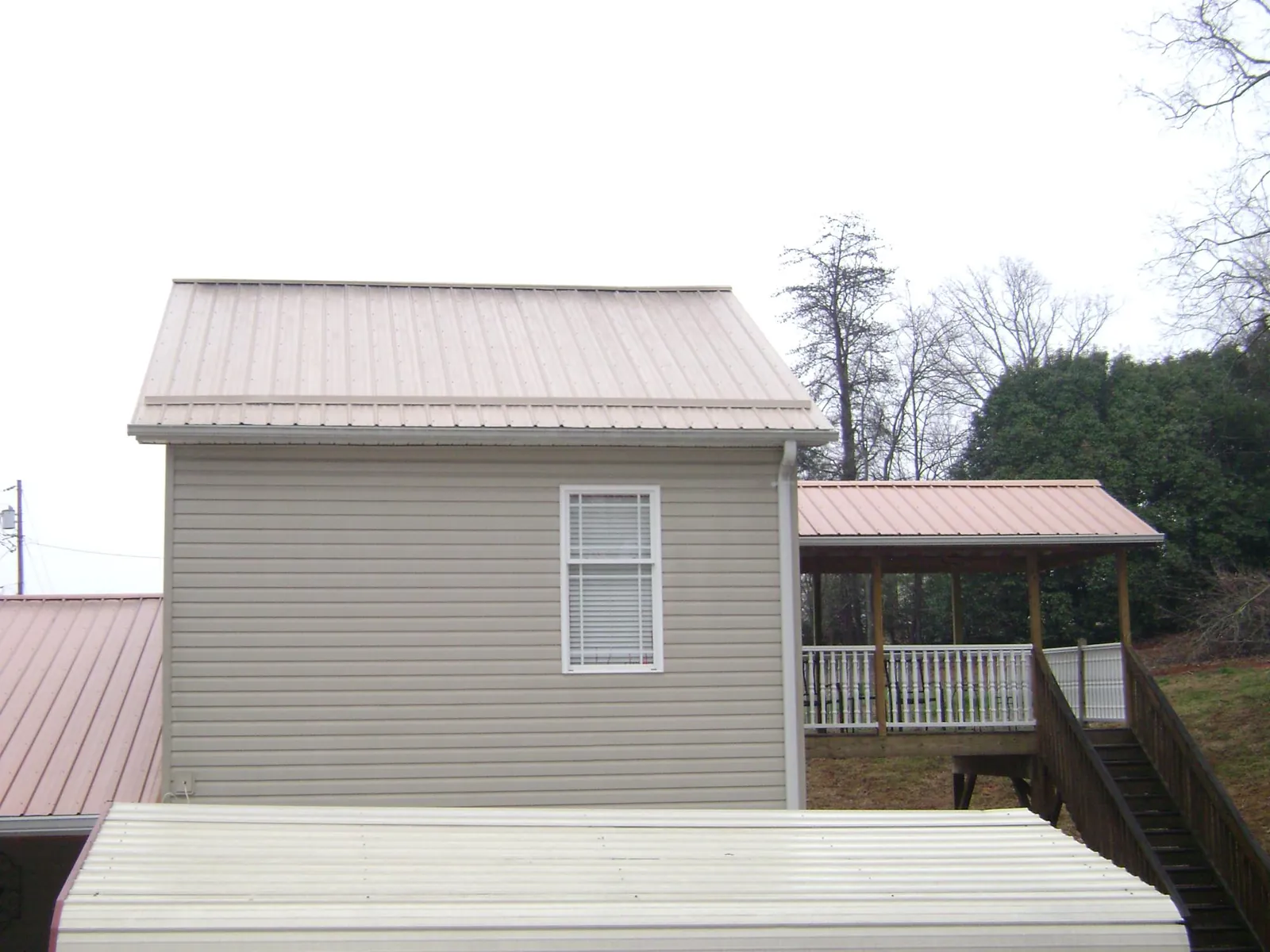 Tan metal roofs on a two story addition and attached porch, from a Roof Replacement job in North Truro