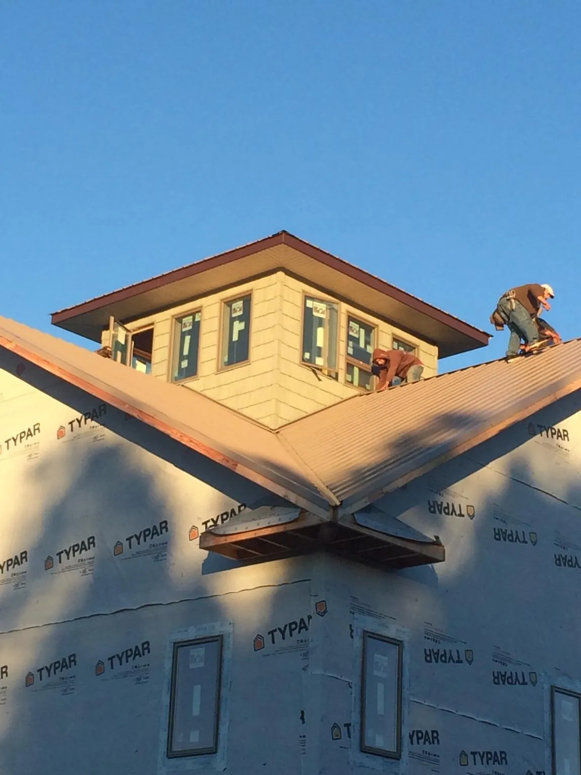 Roofers working around a rooftop cupola on a new metal roof at sunset — Roof Waterproofing in North Truro by Roofing Brothers